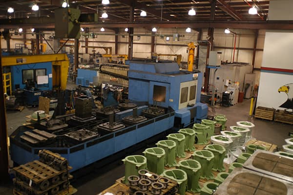 Horizontal machining cell with green cast iron parts staged for machining