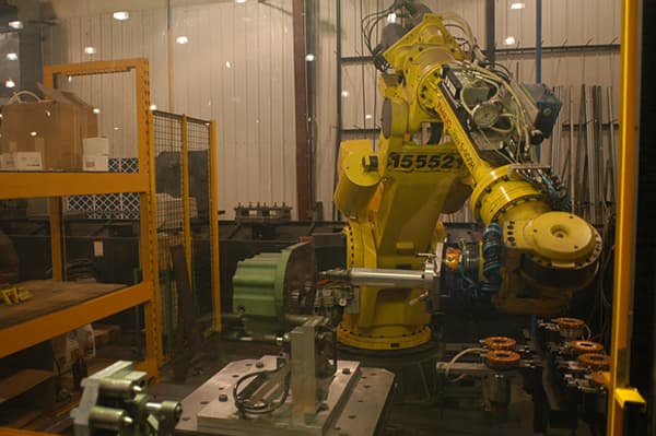 Yellow robot arm loading parts in a work cell