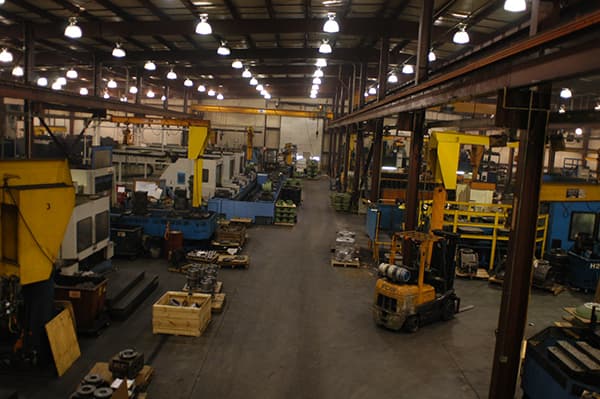 Main production aisle with overhead jib cranes and a forklift